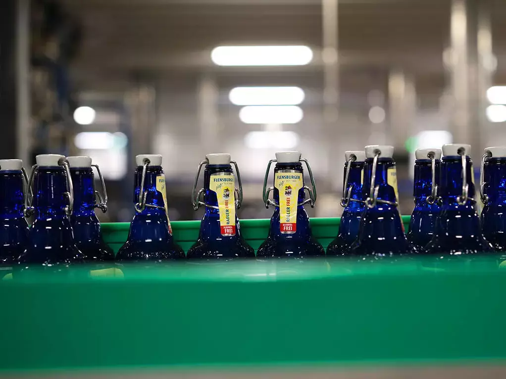 Blaue Bierflaschen, die mit Radler Frei befüllt werden, in der Abfülllinie.