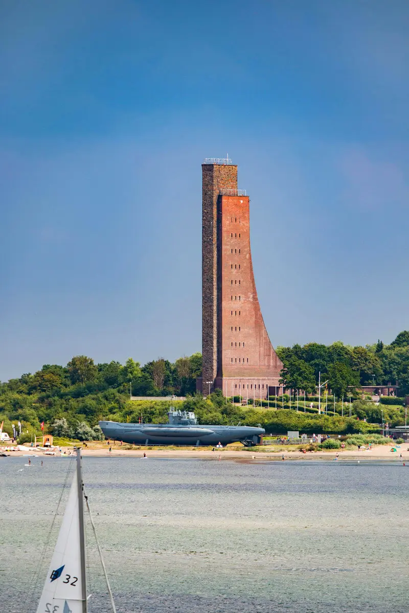 Marine-Ehrenmal Laboe mit U-Boot-Museum am Ostseestrand und Segelboot im Vordergrund.