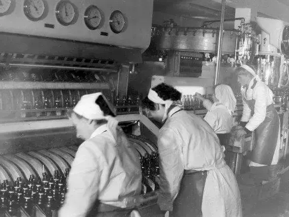 Historische Aufnahme von Frauen am Arbeiten an der Flaschen-Waschanlage in der Abfüllung bei FLENS.